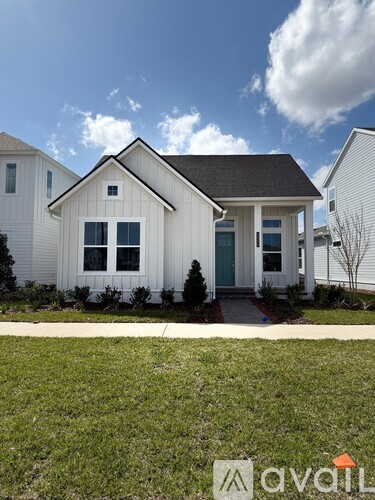 A white house with a black roof and a small front yard.
