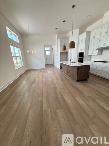 A spacious kitchen with wooden flooring and white cabinetry.