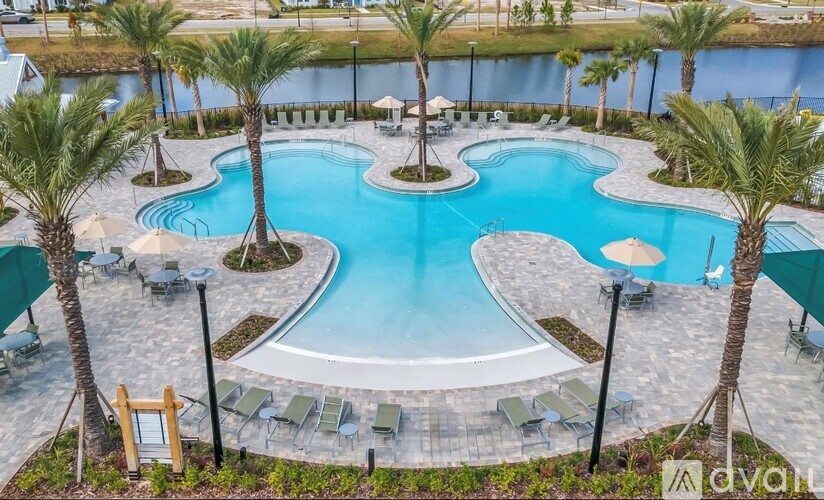 A large outdoor swimming pool surrounded by palm trees and lounge chairs.