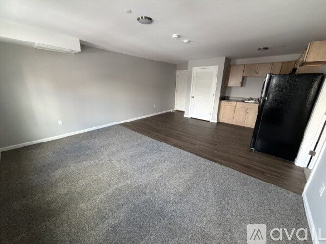 A spacious kitchen with a black fridge and wooden cabinets.