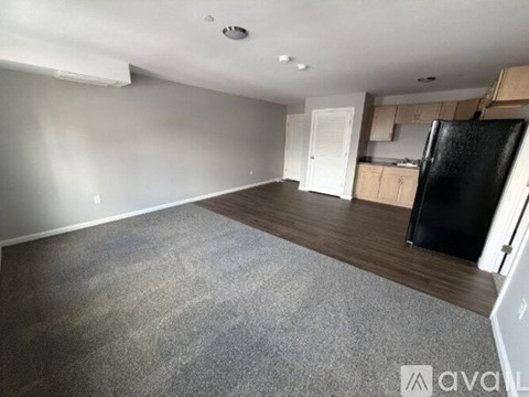 A spacious kitchen with a black fridge and wooden cabinets.