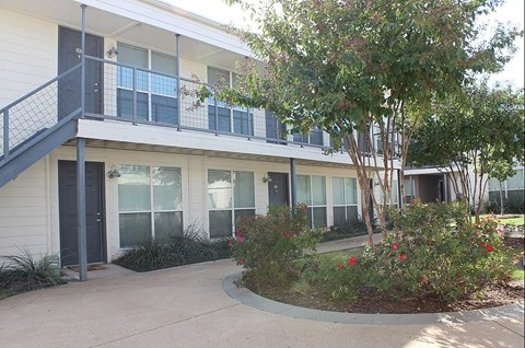 A building with a balcony and a tree in front.