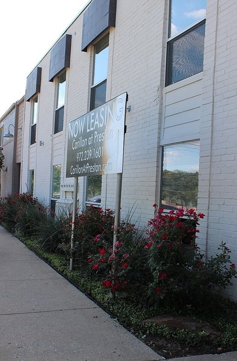 A building with a sign that says "NOW LEASING" on it.