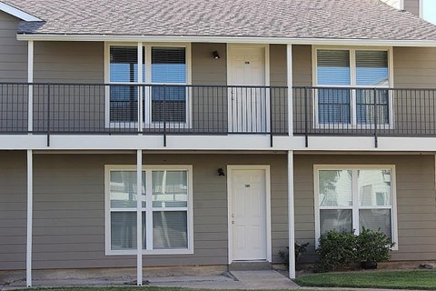 A two-story house with a balcony and a white door.
