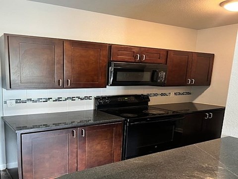 A kitchen with brown cabinets and black appliances.