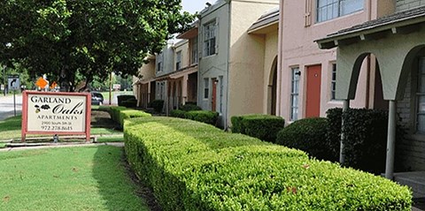 A sign for Garland Apartments is in front of a row of houses.