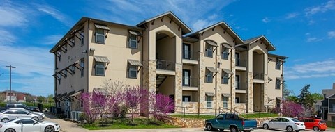 A large apartment building with a parking lot in front.