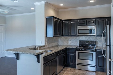 A kitchen with black cabinets and stainless steel appliances.