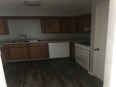 A kitchen with wooden cabinets and a white dishwasher.