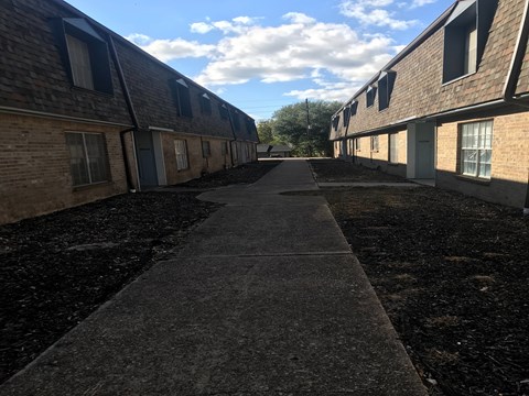 A long concrete pathway leads between two rows of buildings.
