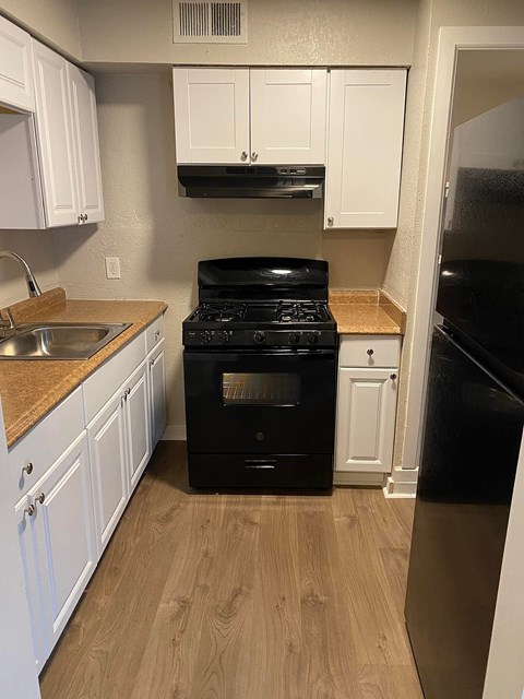 A black stove in a kitchen with white cabinets.