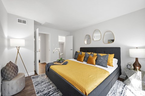 A bedroom with a yellow bedspread and a grey headboard.