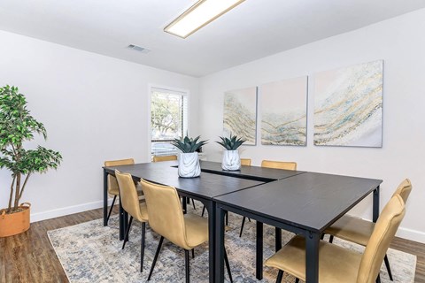 A dining room with a black table and chairs.