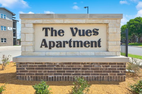 A sign that says "The Vues Apartment" in front of a building.