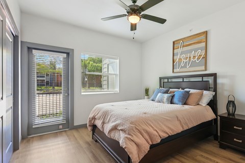 A bedroom with a bed, a ceiling fan, and a window with blinds.