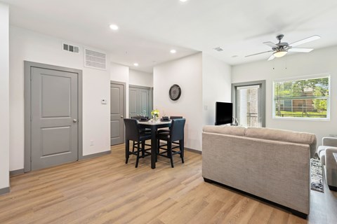 A modern dining room with a wooden floor and a ceiling fan.
