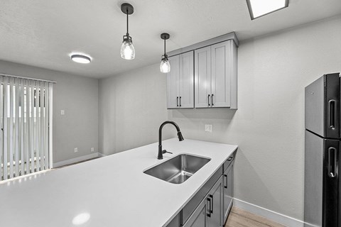 A kitchen with a white countertop and a black refrigerator.