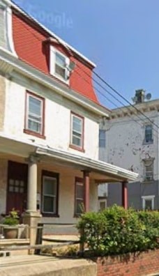 A white house with a red roof and a porch.