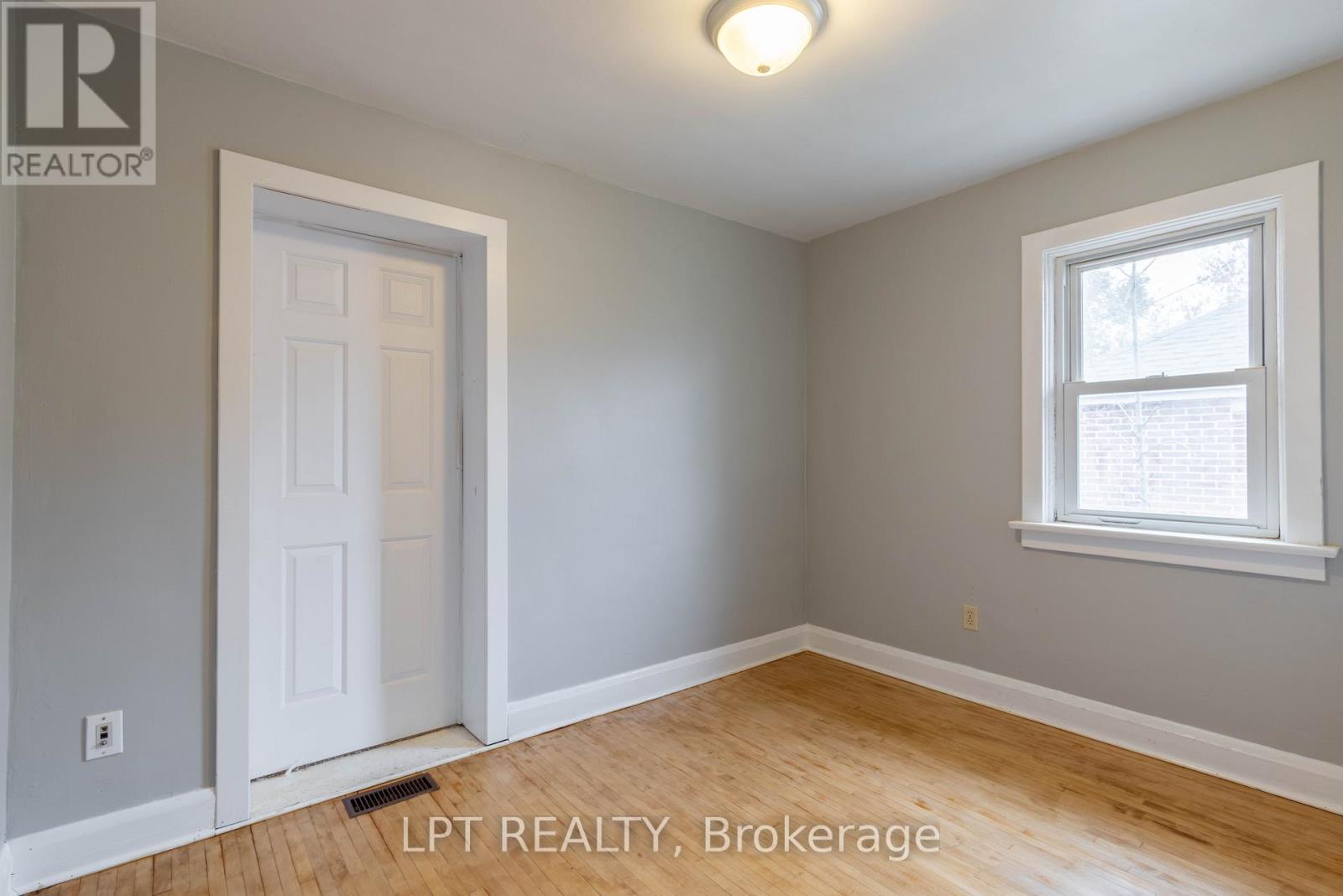 A room with a white door and a window with a view of trees outside.