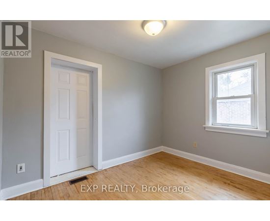 A room with a white door and a window with a view of trees outside.