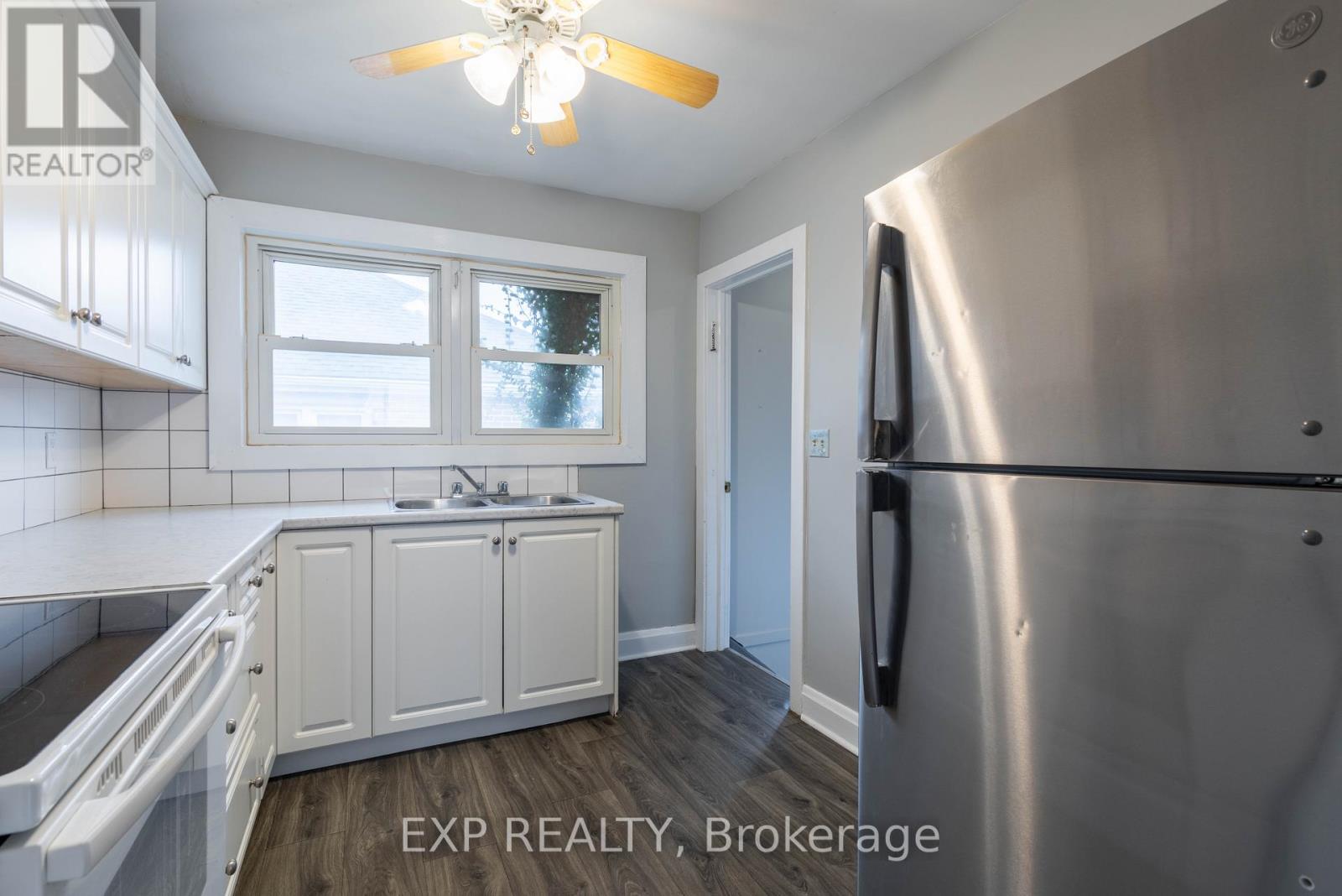 A kitchen with white cabinets and a stainless steel refrigerator.