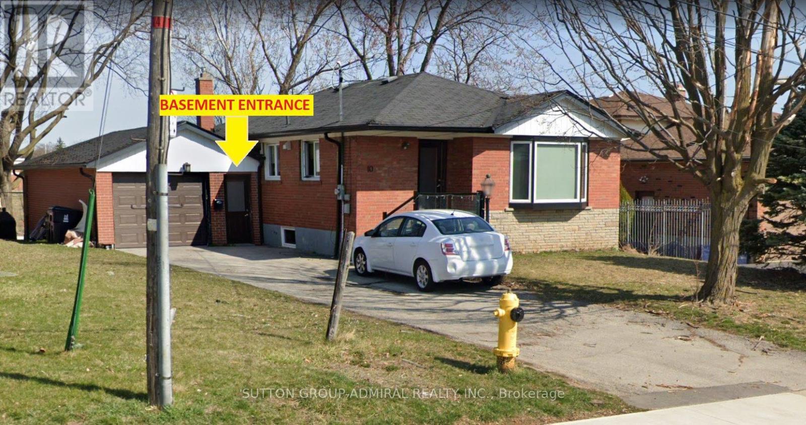 A signpost in front of a house with a yellow arrow pointing to the basement entrance.