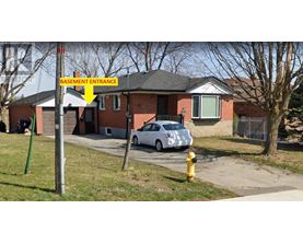 A signpost in front of a house with a yellow arrow pointing to the basement entrance.