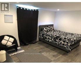 A bedroom with a black and white bed and a black chair.