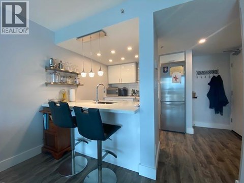 A kitchen with a table and chairs in the foreground and a hallway in the background.