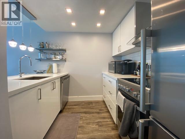 A modern kitchen with white cabinets and stainless steel appliances.