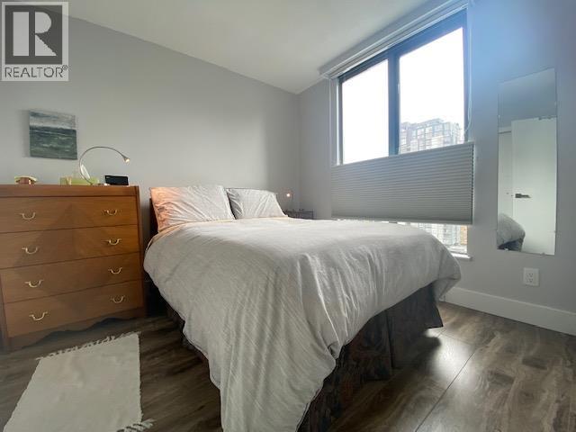 A bedroom with a bed, dresser, and window.