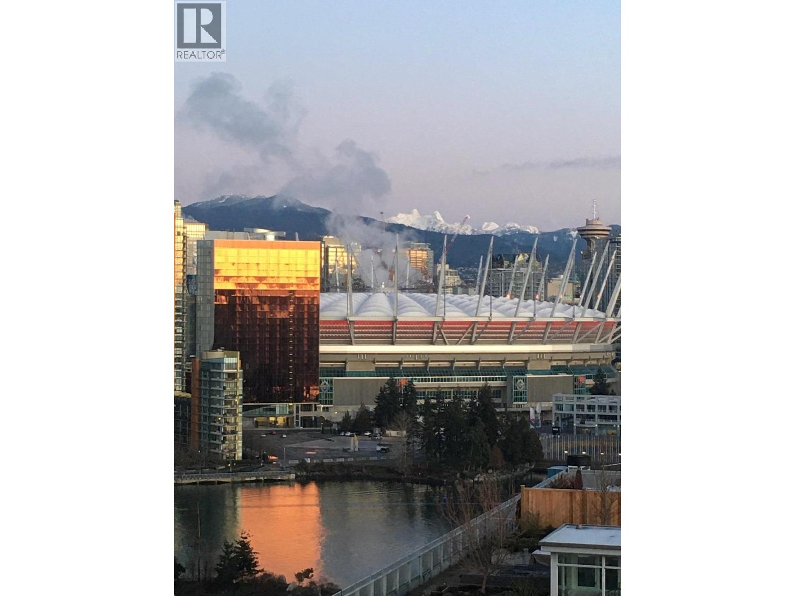 A cityscape with a mountain in the background and a building with a large glass facade in the foreground.