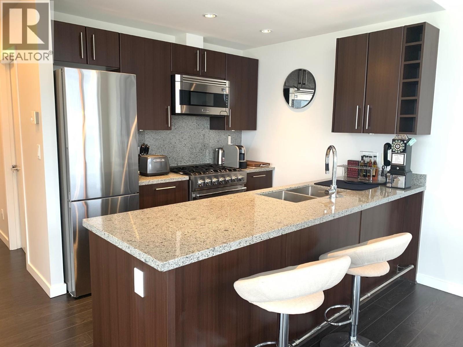 A kitchen with brown cabinets and a granite countertop.