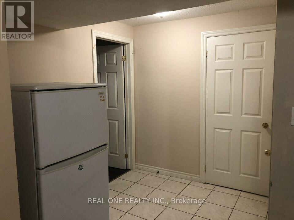 A white refrigerator is in a kitchen with white walls and a white door.