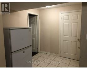 A white refrigerator is in a kitchen with white walls and a white door.