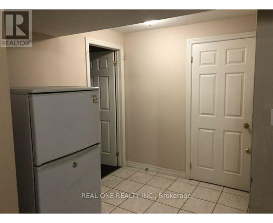 A white refrigerator is in a kitchen with white walls and a white door.