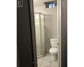 A white toilet in a small bathroom with a glass shower door.