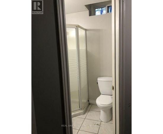 A white toilet in a small bathroom with a glass shower door.