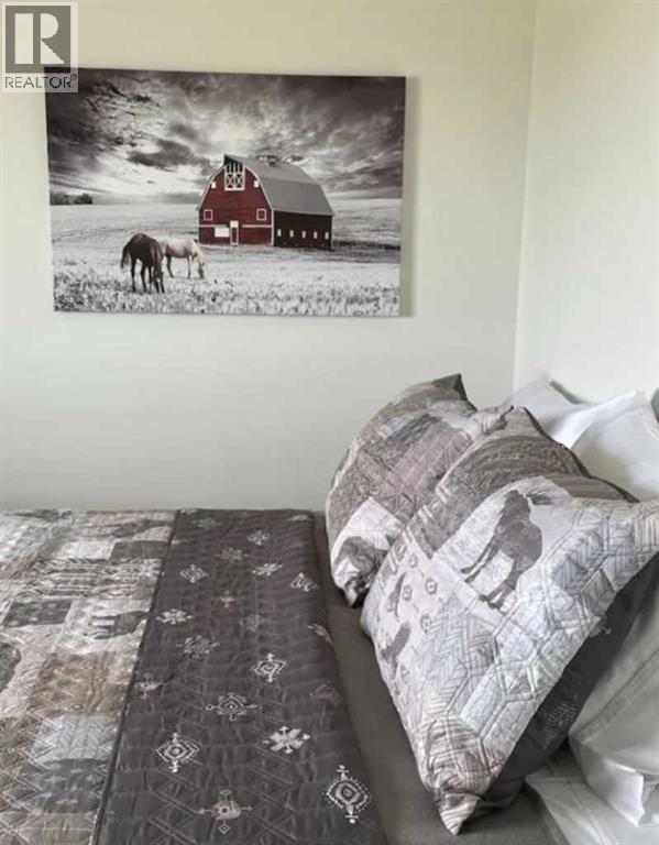 A bedroom with a bed and a picture of a red barn on the wall.