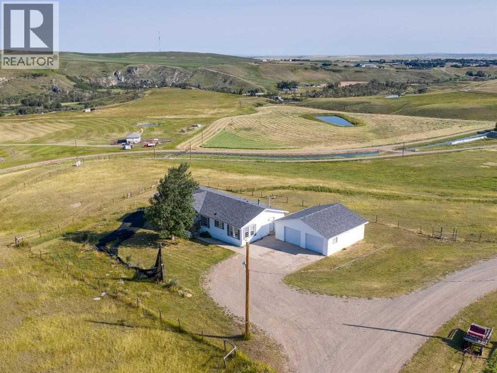 A house with a driveway in the foreground and a grassy field in the background.