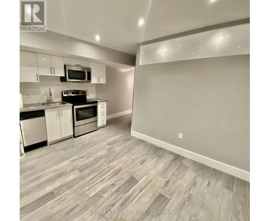 A kitchen with a microwave above the stove and a counter with a sink.