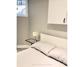 A bedroom with a bed, a nightstand with a lamp, and a framed picture on the wall.