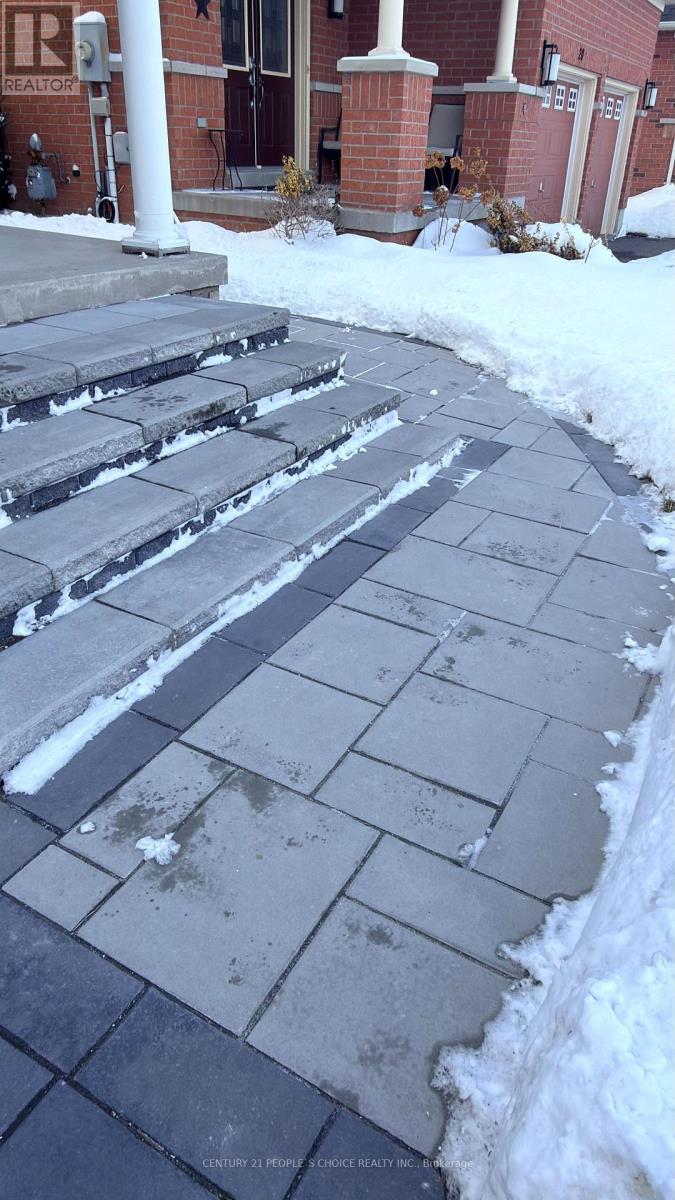 A snow-covered sidewalk in front of a brick building.