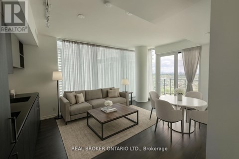 A modern living room with a grey sofa, a coffee table, and a dining table with chairs.