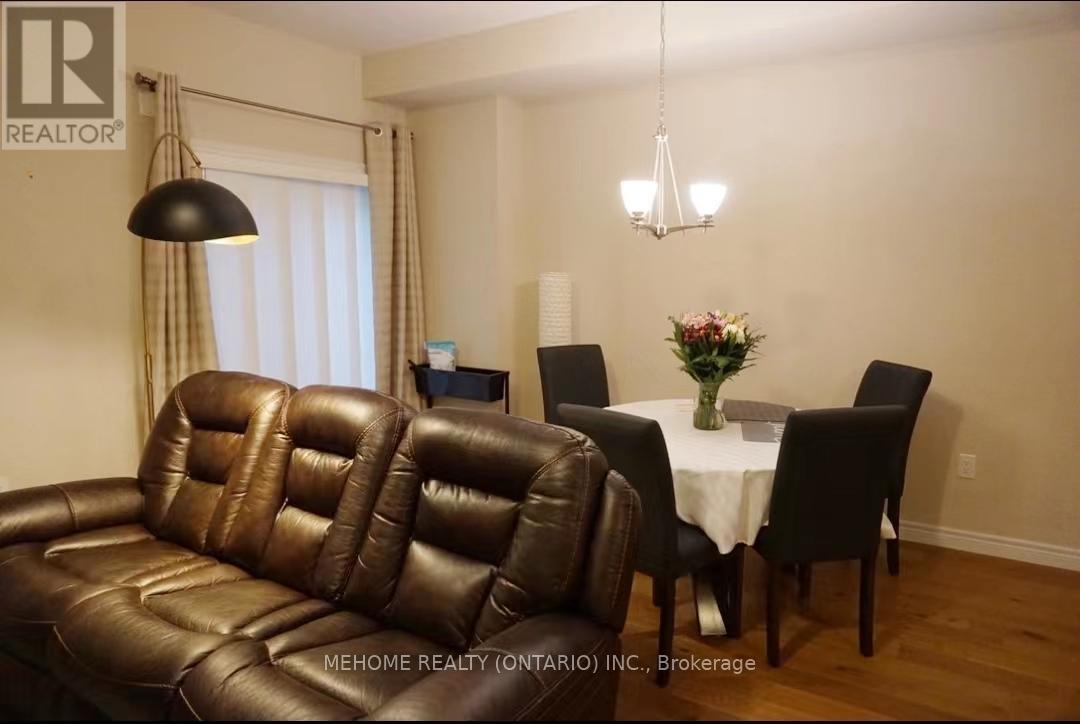 A brown leather couch sits in a room with a dining table and chairs.