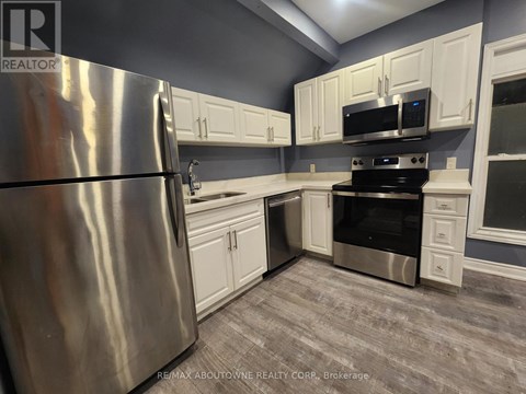 A kitchen with a stainless steel refrigerator and white cabinets.