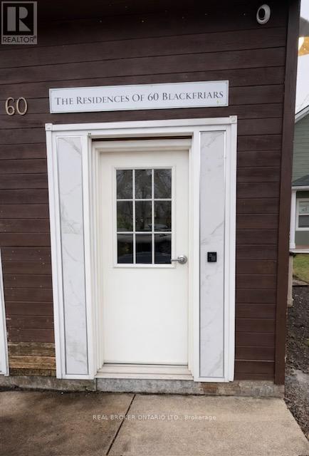 A brown building with a white door and a sign that says "The Residences of 60 Blackfriars".