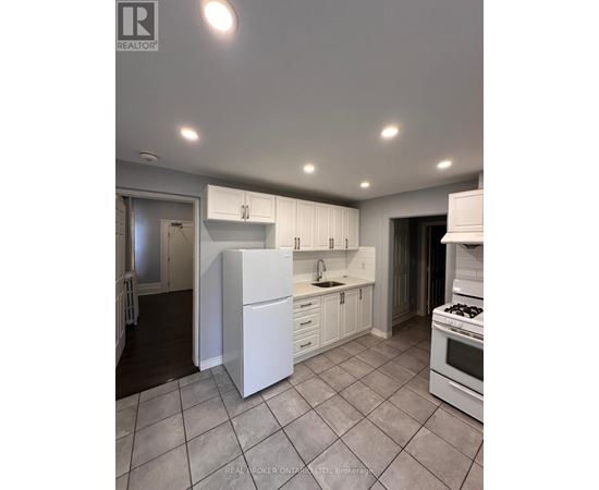 A white kitchen with a refrigerator, sink, and stove.