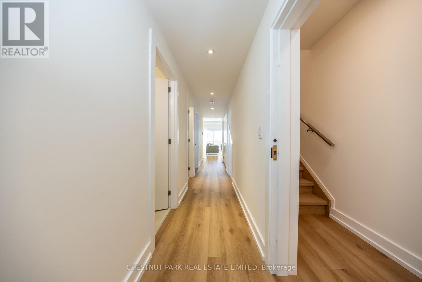 A long hallway with white walls and wood floors.