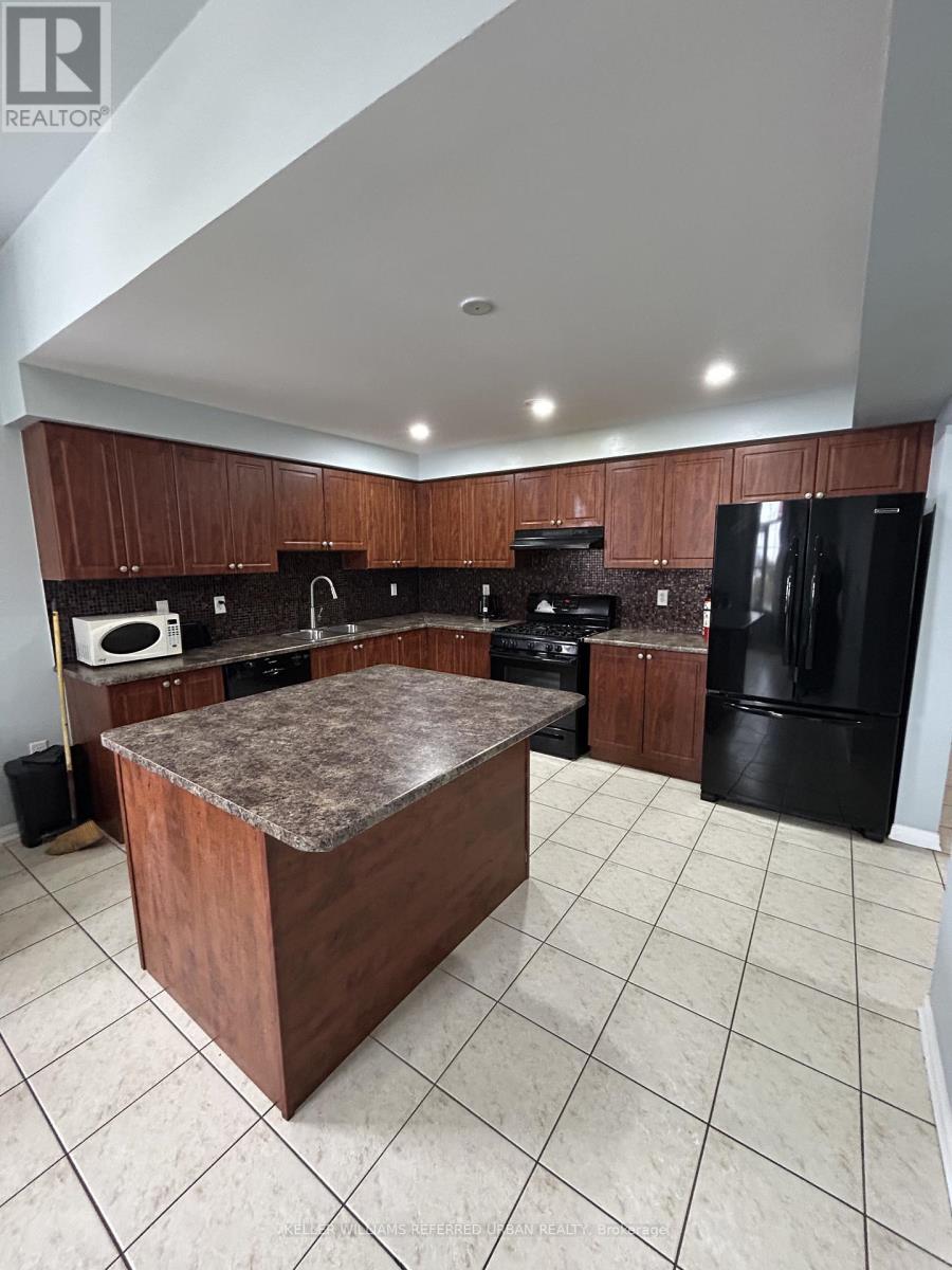 A kitchen with a black refrigerator and brown cabinets.